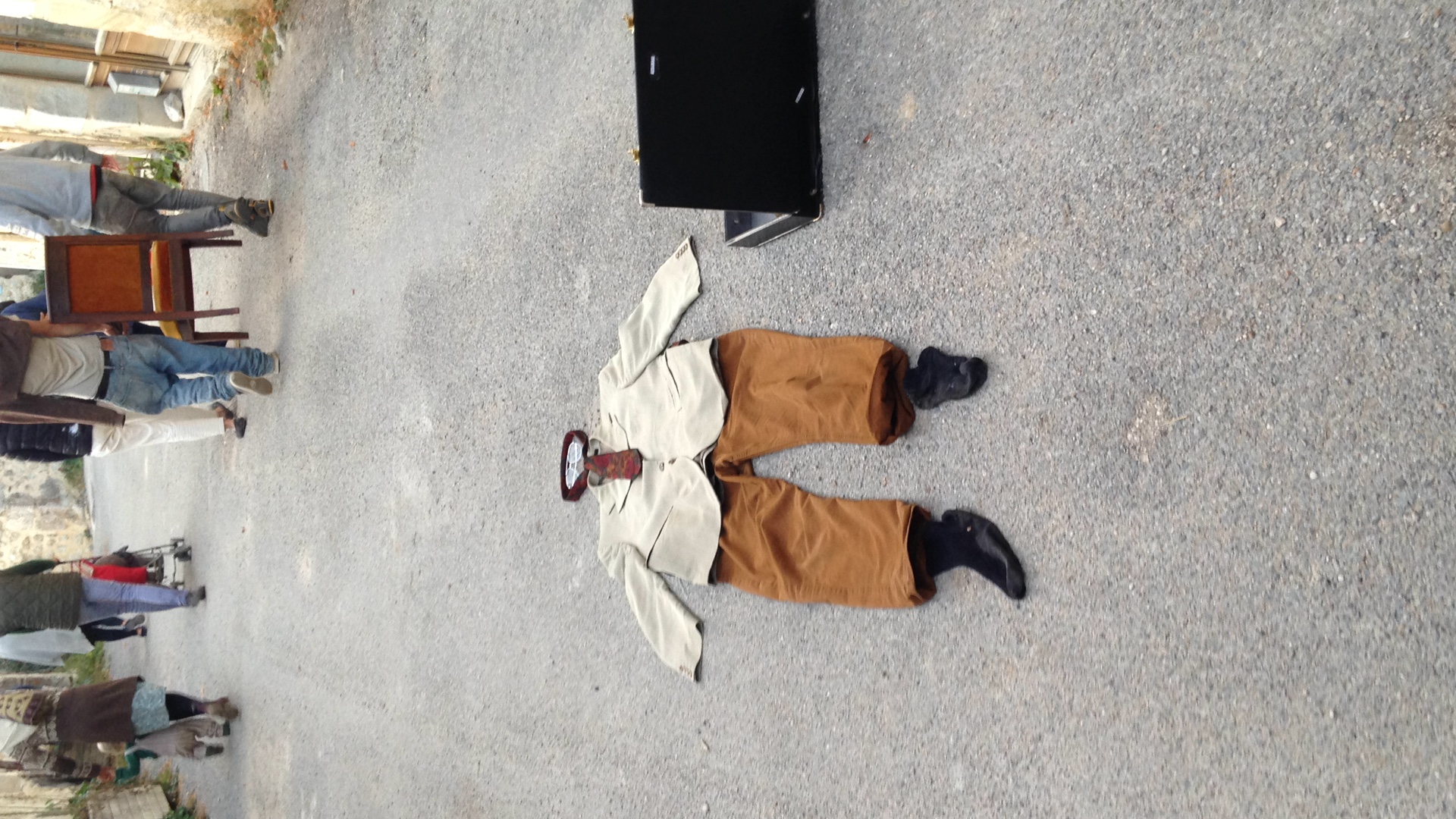 un costume et une valise abandonnée sur la route. au loin des gens s'en vont