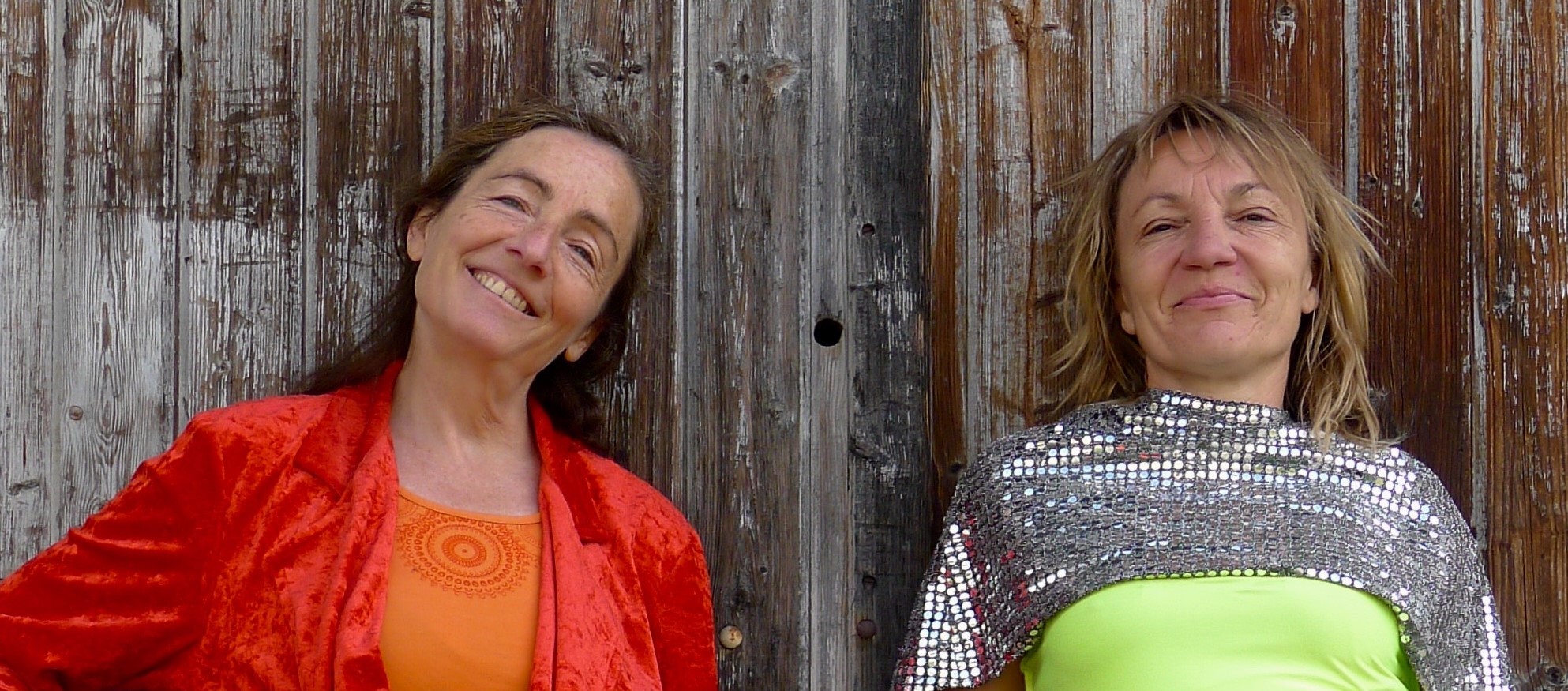 Photographie sur fond de jardin de Valérie Surdey & Catherine Mouton en costumes noirs et blancs, pieds en l'air, en bottes à talons - fondatrices de la Cie Rouge Virgule